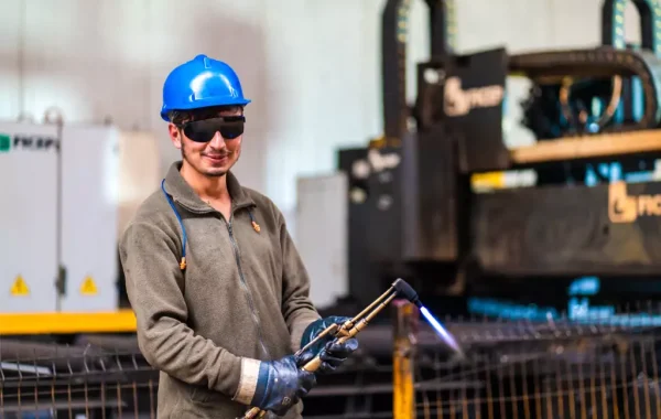 A smiling welder cutting metal in a fabrication shop, part of mobile torch cutting in Illinois