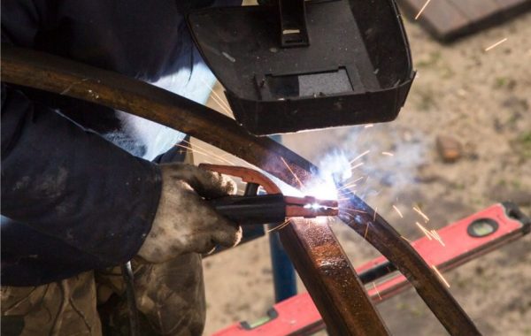 A welder working on an end piece of metal, helping to repair it for future use