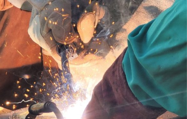 A closeup of a welder performing mobile metal repair for a piece of industrial equipment